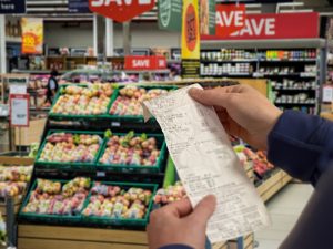 A person holding a receipt in a grocery store. Rising prices can feel daunting. Learn how you can adjust your budget for inflation.