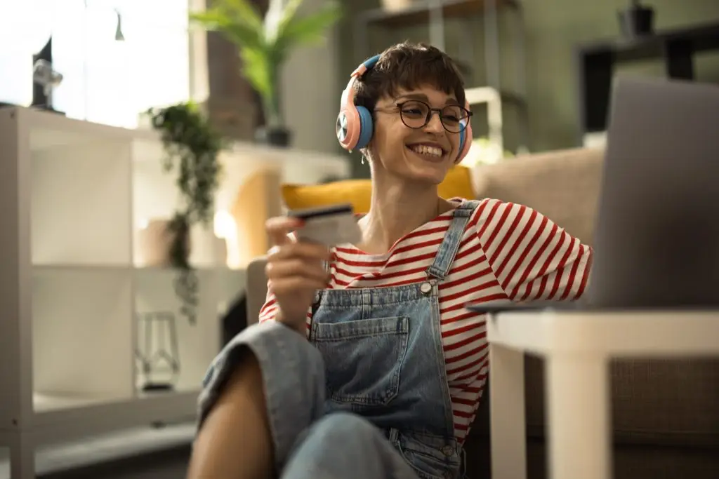 Happy young woman shopping online and vibing with music