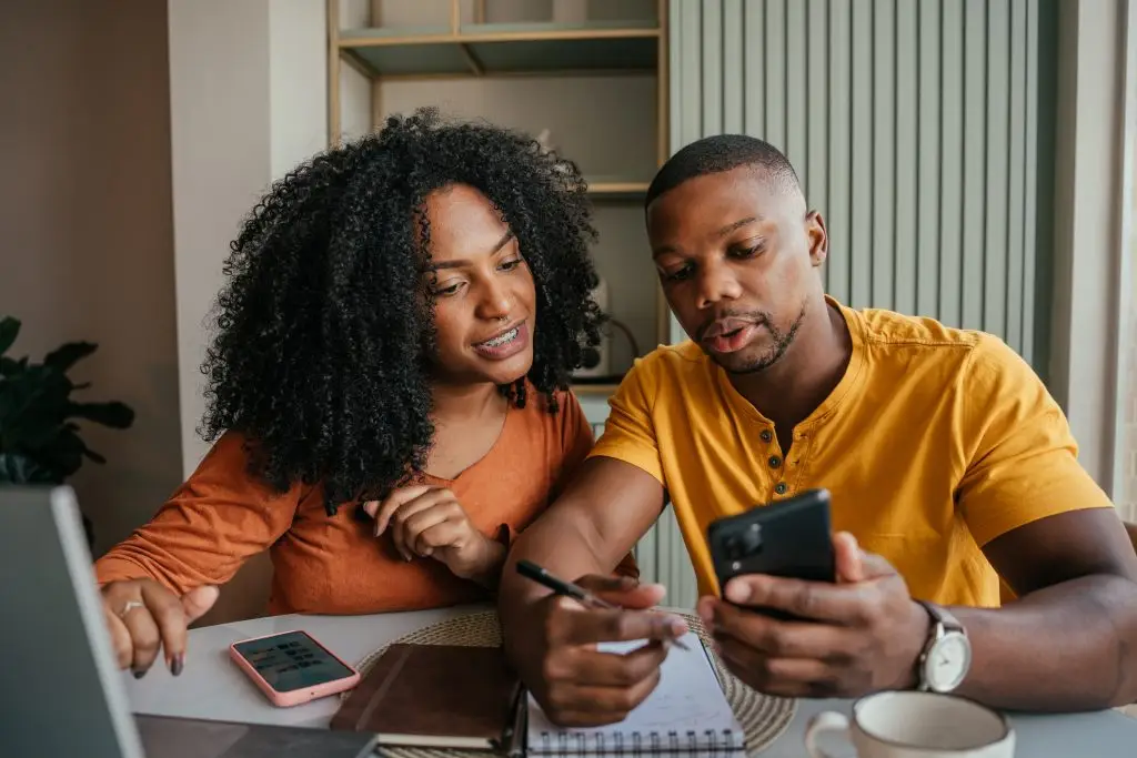 Young couple adding to their savings account on a smartphone